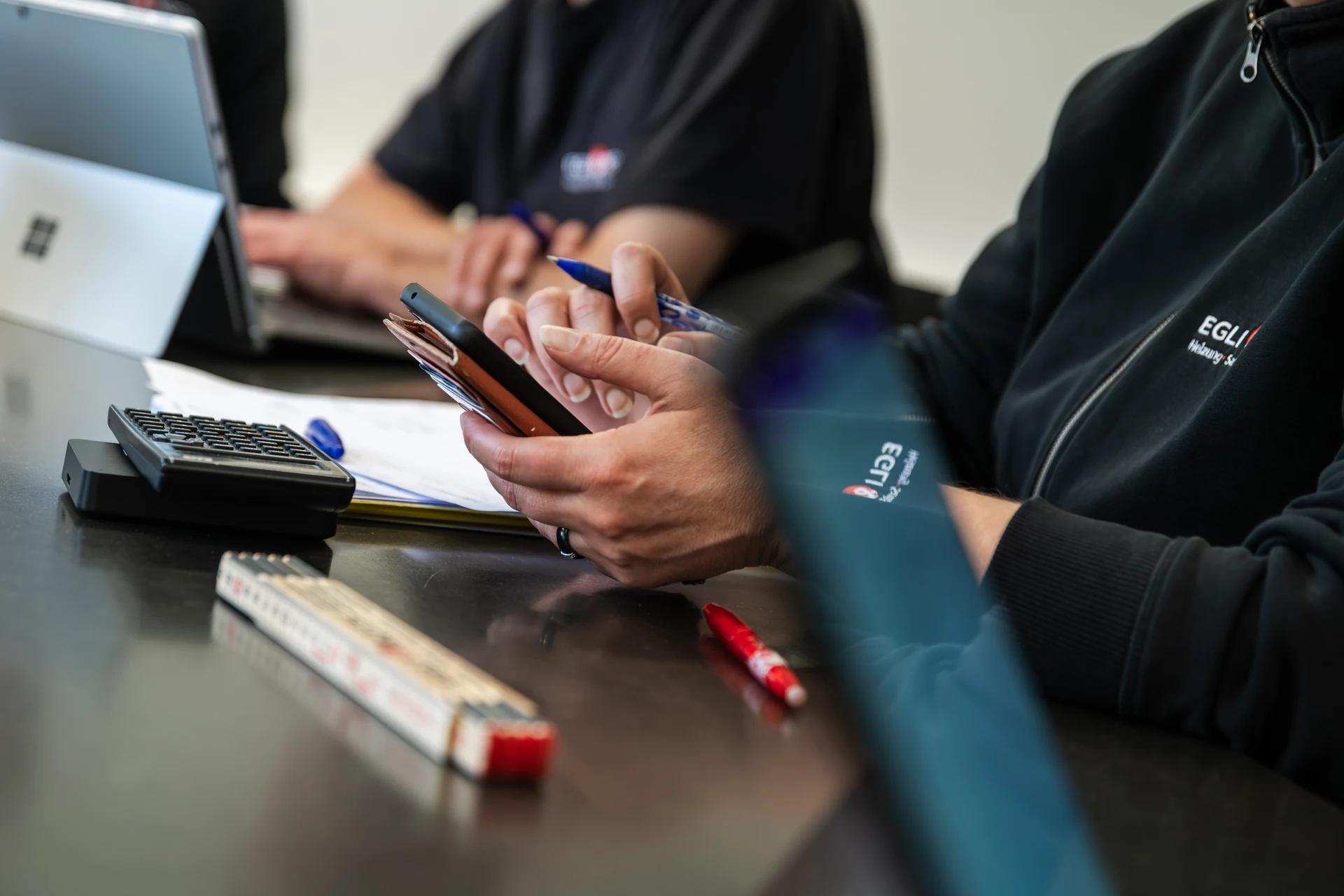 Besprechung am Tisch mit Smartphone, Notizen und Laptop