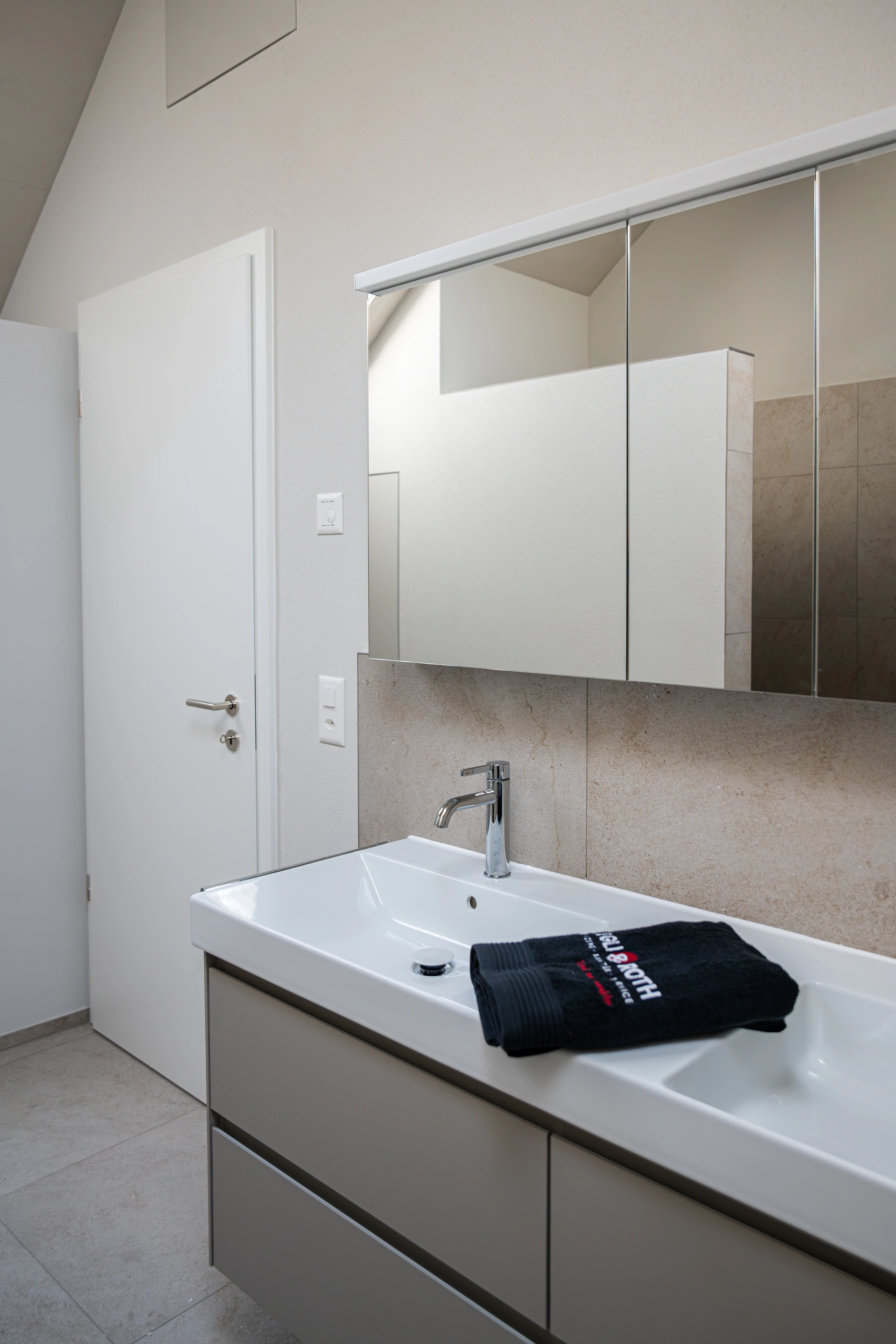 Heller Waschtisch mit Spiegelschrank und gefalteten Handtüchern