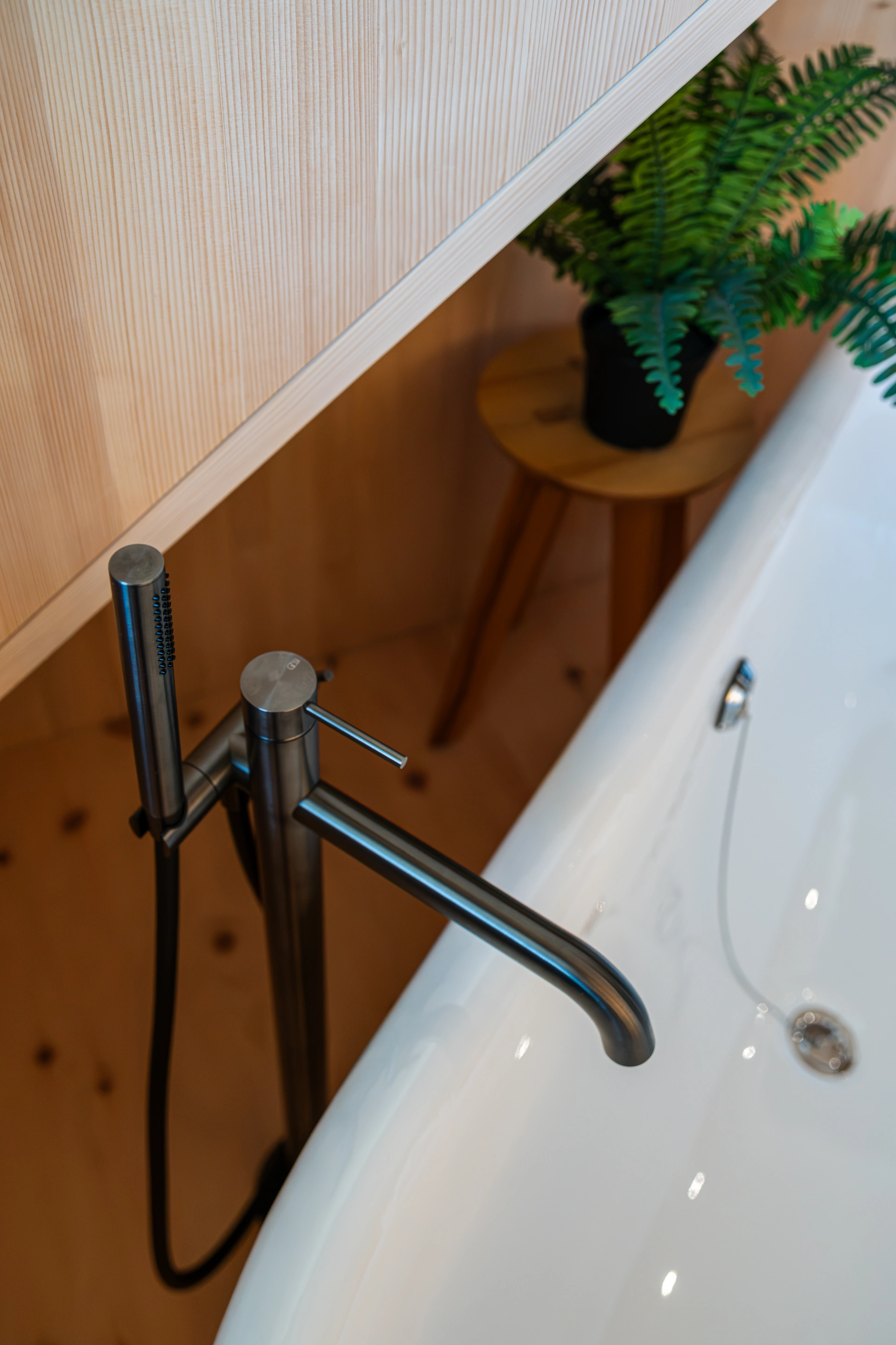 Badewannenarmatur vor einer Holzwand
