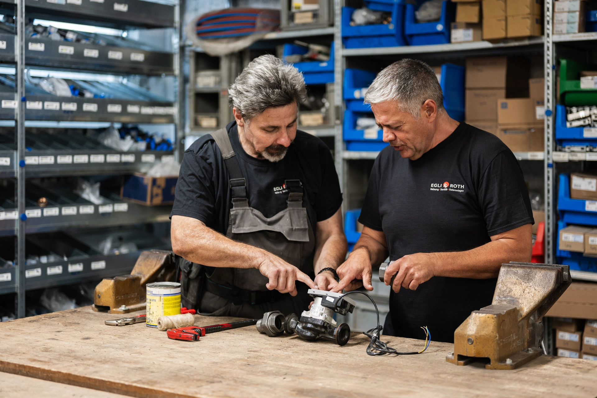 Zwei Mitarbeiter besprechen eine Pumpe an der Werkbank