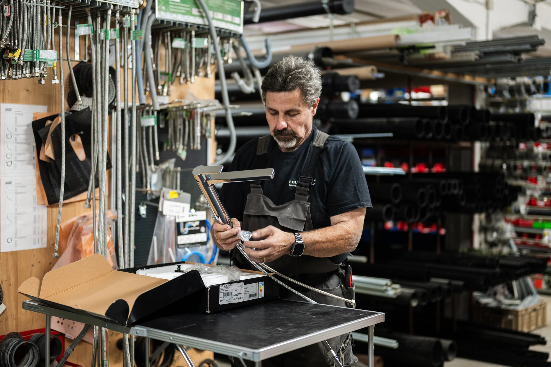 Mitarbeiter prüft ein Bauteil im Materiallager